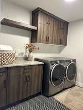 Washroom with cabinet space, washer and clothes dryer, and tile patterned floors