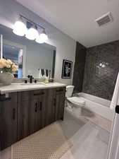 Full bathroom with vanity, shower / bath combination, light tile patterned flooring, and a textured ceiling