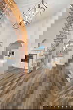 Hall featuring dark wood finished floors, arched walkways, a chandelier, and a high ceiling