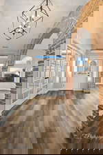 Entryway featuring french doors, wood finished floors, a chandelier, and vaulted ceiling