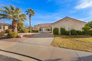 Mediterranean / spanish house with a tiled roof, driveway, stucco siding, and a front lawn
