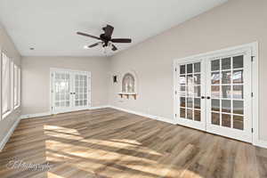 Empty room with french doors, vaulted ceiling, a ceiling fan, and wood finished floors