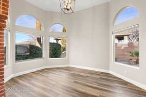 Unfurnished dining area with light wood-style floors, a chandelier, and a towering ceiling