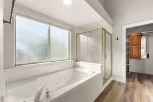 Full bath with a shower stall, plenty of natural light, a jetted tub, wood finished floors, and recessed lighting