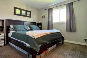 Bedroom with dark carpet and baseboards