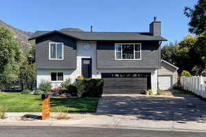 Bi-level home featuring brick siding, driveway, an attached garage, and a chimney