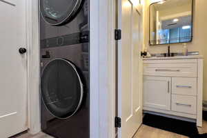 Washroom featuring light wood-style floors and stacked washer / drying machine