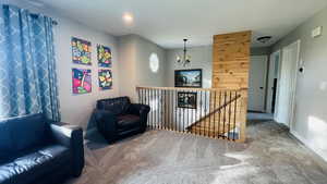 Sitting room featuring carpet, an upstairs landing, and a chandelier
