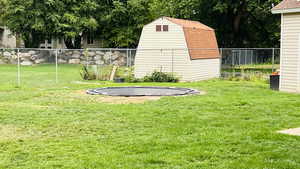 View of yard with a trampoline, a storage shed, and view of wooded area