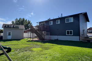 Back of property featuring stairway, a wooden deck, a shed, and a chimney