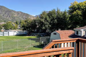 Fenced backyard with a storage shed, a mountain view, and a balcony