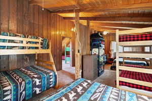 Loft with vaulted ceiling, carpeted floor, and wooden walls and ceiling.