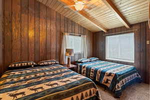 Loft with vaulted ceiling, carpeted floor, and wooden walls and ceiling.