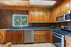 Kitchen featuring appliances with stainless steel finishes, brown cabinetry, light tile-patterned floors.