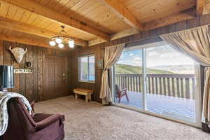 Living room featuring wooden walls, a chandelier, carpet flooring, a mountain view, and a wooden ceiling with exposed beams