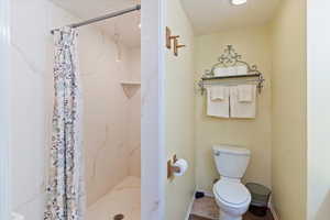 Bathroom with a marble finish shower, and toilet