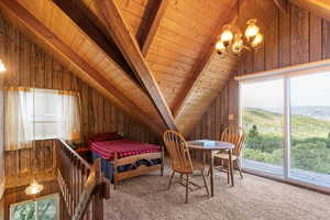 Loft with vaulted ceiling, carpeted with wooden walls and ceiling.