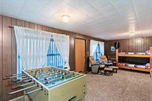 Game room featuring carpet floors and wood walls