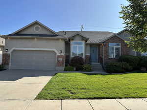 Ranch-style home with stucco siding, a front lawn, concrete driveway, and brick siding
