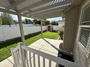 Fenced backyard featuring a patio, a storage unit, and a pergola