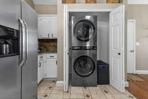 Washroom with light tile patterned floors and stacked washer / dryer