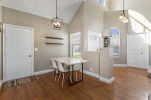 Dining room with dark wood-style floors and high vaulted ceiling