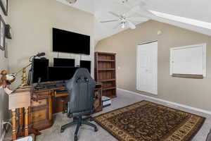Carpeted office featuring a ceiling fan, a skylight, and vaulted ceiling