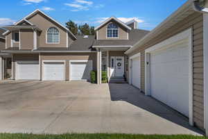 View of front facade with a shingled roof, a garage, driveway, and a chimney