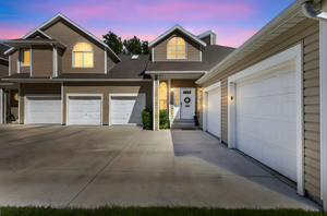 Traditional home featuring roof with shingles, a garage, driveway, and a chimney