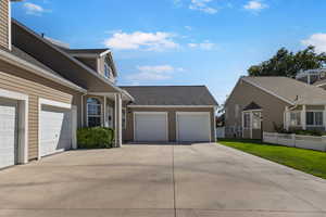 View of side of property with driveway, a shingled roof, a lawn, and an attached garage