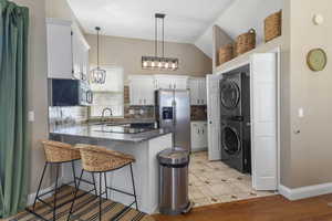 Kitchen with backsplash, stainless steel appliances, dark stone countertops, a breakfast bar, and white cabinetry