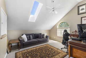 Office area with a textured ceiling, lofted ceiling, a skylight, carpet flooring, and a ceiling fan