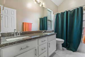 Bathroom with double vanity, curtained shower, and light marble finish floors