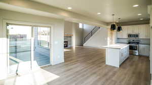 Kitchen featuring recessed lighting, open floor plan, stainless steel appliances, white cabinets, and a center island