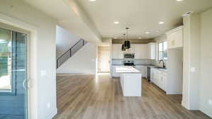 Kitchen with light countertops, a center island, recessed lighting, white cabinetry, and hanging light fixtures