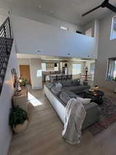 Living area featuring wood finished floors, stairs, a towering ceiling, and recessed lighting