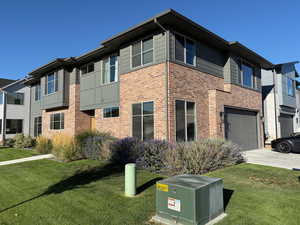View of property exterior with a yard, brick siding, and concrete driveway