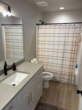 Full bathroom with shower / bath combination with curtain, vanity, dark wood-type flooring, and recessed lighting