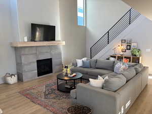 Living area with a tiled fireplace, light wood-style floors, and stairs
