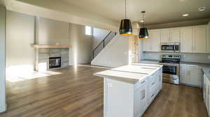 Kitchen with open floor plan, stainless steel appliances, white cabinets, a center island, and decorative light fixtures