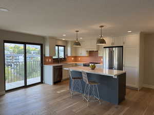 Kitchen featuring a kitchen breakfast bar, recessed lighting, decorative backsplash, cream cabinetry, and a center island