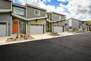 View of front of property with a residential view, concrete driveway, a garage, and stone siding