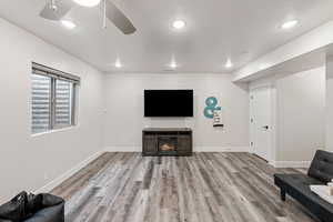 Sitting room with recessed lighting, light wood-style flooring, ceiling fan, and a warm lit fireplace