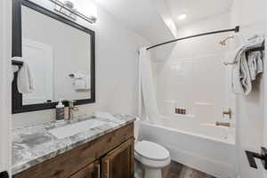 Full bath featuring shower / tub combo, vanity, and dark wood finished floors