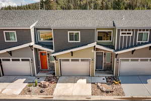 View of front of house with driveway and roof with shingles