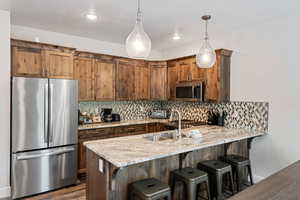 Kitchen with appliances with stainless steel finishes, backsplash, a kitchen breakfast bar, and recessed lighting