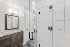 Bathroom featuring a shower stall, vanity, and dark wood-style floors