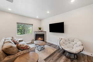 Living room featuring wood finished floors, recessed lighting, and a glass covered fireplace