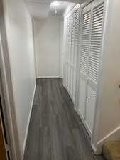 Corridor featuring baseboards and dark wood-style floors
