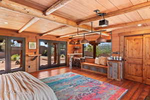 Bedroom featuring wood walls, dark wood finished floors, a wood ceiling with exposed beams, french doors, and access to exterior